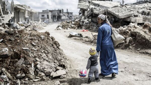 امرأة سورية كردية مع طفل على انقاض مدينة عين العرب (كوباني) - سبوتنيك عربي