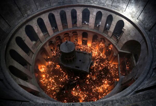 المصلين المسيحيين الأرثوذكسيين يشعلون الشموع من النار المقدسة في كنيسة القيامة في مدينة القدس القديمة - سبوتنيك عربي