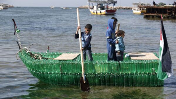 أطفال فلسطينيون على متن قارب مصنوع من الزجاجات البلاستيكية في ميناء مدينة غزة - سبوتنيك عربي