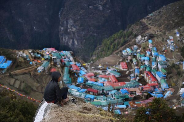حمال نيبالي ميلان راي يبلغ من العمر 14 عاما يستريح على رأس قمة صخرية في الجزء العلوي من قرية بازار، التي تقع في الطريق إلى قمة إيفرست - سبوتنيك عربي