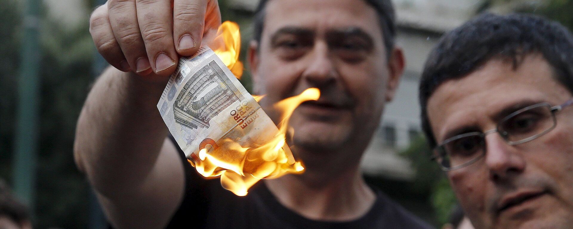 متظاهر يوناني يحرق عملة اليورو خلال مسيرة إحتجاجية ضد الإتحاد الأوروبي فى أثينا - سبوتنيك عربي, 1920, 02.03.2022