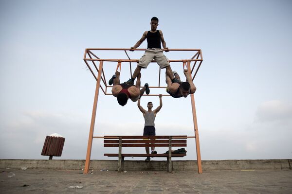 عدد من الشباب الفلسطيني يمارس تمارين رياضية في أحد الشوارع على ساحل البحر في غزة - سبوتنيك عربي