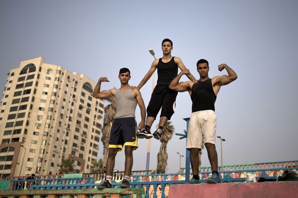 شباب غزة يعرضون عضلاتهم في أحد الشوارع بالقرب من شاطئ البحر - سبوتنيك عربي