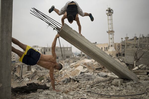 الفسلطينيون يمارسون تمارين اللياقة البدنية في الهواء الطلق على أنقاض الأبنية في شوارع غزة - سبوتنيك عربي