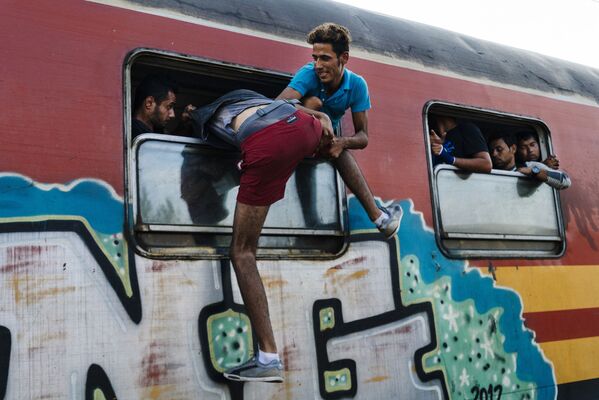 مهاجرون يحاولون الصعود الى  القطار في محطة قطارات غيفيغليا - سبوتنيك عربي