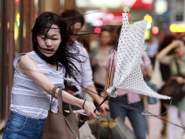 فتاة تحاول فتح المظلة أثناء إعصار المحيط الهادئ سوديلور في تايتشو، الصين - سبوتنيك عربي