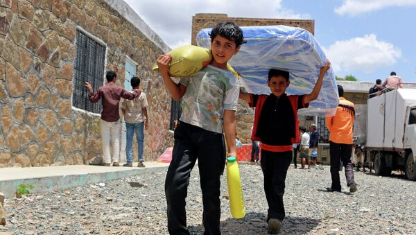 Boys carry relief supplies to their families who fled fighting in the southern city of Aden, during a food distribution effort by Yemeni volunteers, in Taiz, Yemen. - سبوتنيك عربي