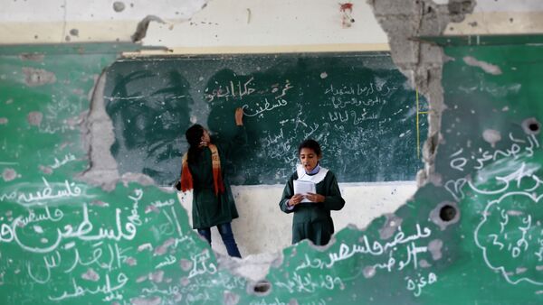 Palestinian girls play inside their school which was destroyed during the 50 days of conflict between Israel and Hamas last summer, in the Shejaiya neighborhood of Gaza City, on November 5, 2014 - سبوتنيك عربي