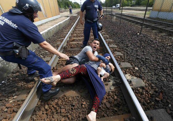 عناصر من الشرطة الهنغارية يحاولون منع أسرة من المهاجرين من العبور عبر محطة للسكك الحديدية المجر، 3 سبتمبر 2015. - سبوتنيك عربي