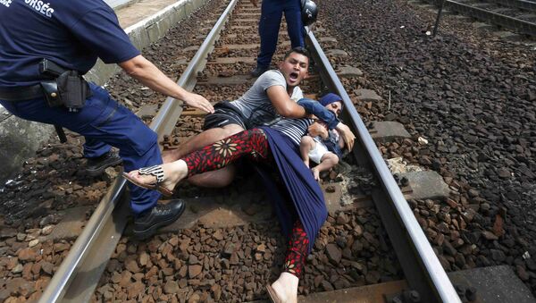 عناصر من الشرطة الهنغارية يحاولون منع أسرة من المهاجرين من العبور عبر محطة للسكك الحديدية المجر، 3 سبتمبر 2015. - سبوتنيك عربي