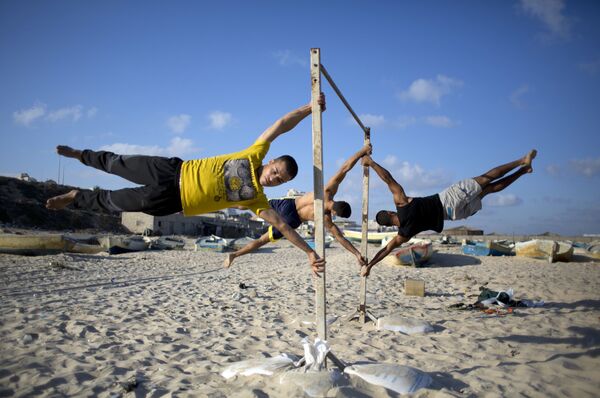 شبان فلسطنيون يمارسون تمارين رياضية على شاطئ ساحل قطاع غزة. - سبوتنيك عربي