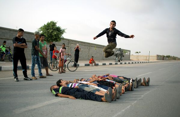 متزلج فلسطيني يقفز فوق الصبية الصغار نيام على الأرض ، وذلك خلال لقائهم الأسبوعي لممارسة رياضتهم في حي الزهراء، في ضواحي مدينة غزة. - سبوتنيك عربي