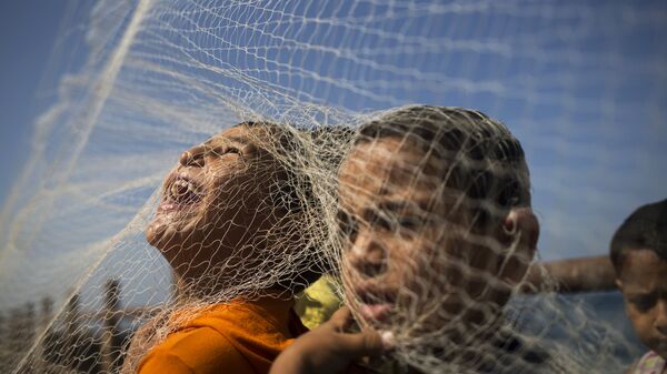 أطفال قطاع غزة يلعبون بشباك صيد السمك - سبوتنيك عربي