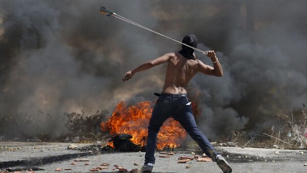 شاب فلسطيني يقذف الحجارة على قوات الاحتلال الإسرائيلي خلال الاشتباكات في بيت ايل - سبوتنيك عربي