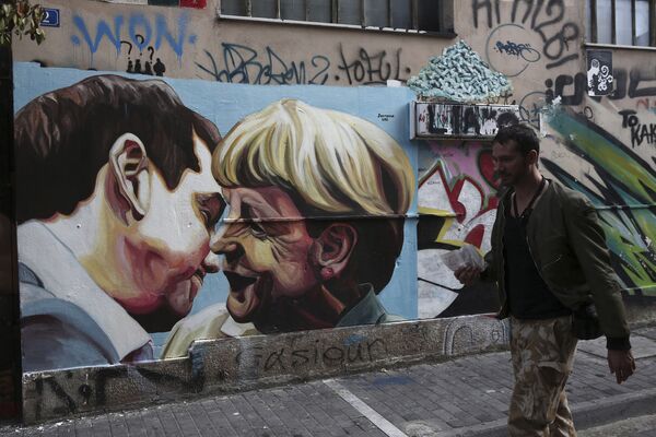 رسم جرافيتي للمستشارة الألمانية أنجيلا ميركل ورئيس الوزراء اليوناني أليكسيس سيبراس على إحدى جدران مدينة اليونان. - سبوتنيك عربي