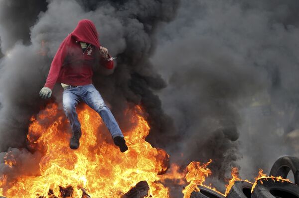 شاب فلسطيني يقفز فوق مجموعة من العجال التي تحترق، وذلك خلال الاشتباكات التي وقعت بين قوات الإحتلال الإسرائيلي والفلسطينيين بالقرب من مستوطنة بيت-إيل، بالقرب من مدينة رام الله في الضفة الغربية، 26 أكتوبر/ تشرين الأول 2015. - سبوتنيك عربي