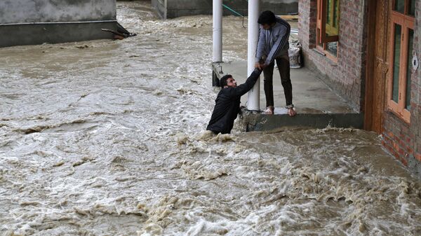 A Kashmiri man stretches his hand to help a local evacuate from a flood affected area in Srinagar, Indian-controlled Kashmir - سبوتنيك عربي