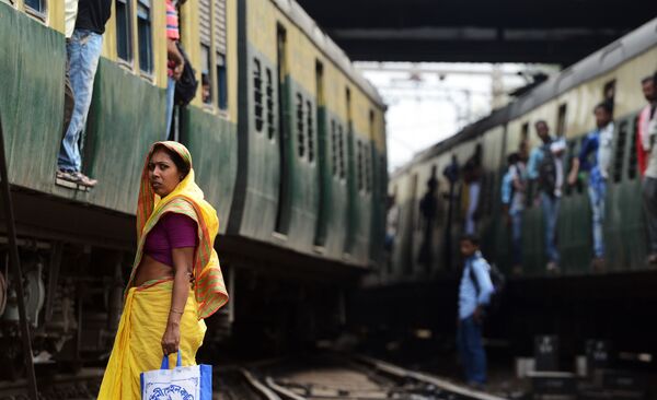 امرأة هندية تنتظر مرور قطار لكي تقطع السكة الحديدية بمحطة القطار في كالكوتا، 25 فبراير/ شباط 2015. وأعلنت وزارة السكك لحديدية، في نفس اليوم،  في الهند، أنها ستوفر كافة محطات القطار بـ الإنترنت اللاسلكي. - سبوتنيك عربي