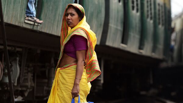 امرأة هندية تنتظر مرور قطار لكي تقطع السكة الحديدية بمحطة القطار في كالكوتا، 25 فبراير/ شباط 2015. وأعلنت وزارة السكك لحديدية، في نفس اليوم،  في الهند أنها ستوفر كافة محطات القطار بـ الانترنت اللاسلكي. - سبوتنيك عربي
