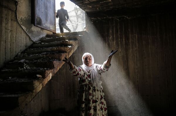 امرأة تقف وسط ركام منزلها إثر اتباكات عنيفة وقتال شديد بين القوات الحكومية التركية والمقاتلين الأكراد على الحدود الجنوبية الشرقية (بالقرب من الحدود مع العراق وسوريا) بالقرب من بلدة جزرة (جزيرة ابن عمر)، 2 مارس/ آذار 2016. - سبوتنيك عربي