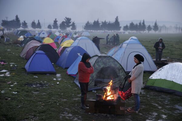 فتيات لاجئات تتدفأن على نار الحطب في إحدى المخيمات على الحدود اليونانية-المقدونية، 1 مارس/ آذار 2016. - سبوتنيك عربي