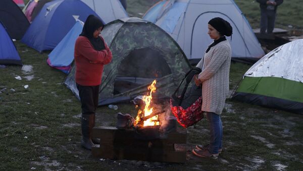 فتيات لاجئات يتدفون على نار الحطب في إحدى المخيمات على الحدود الينونانية-المقدونية، 1 مارس/ آذار 2016. - سبوتنيك عربي