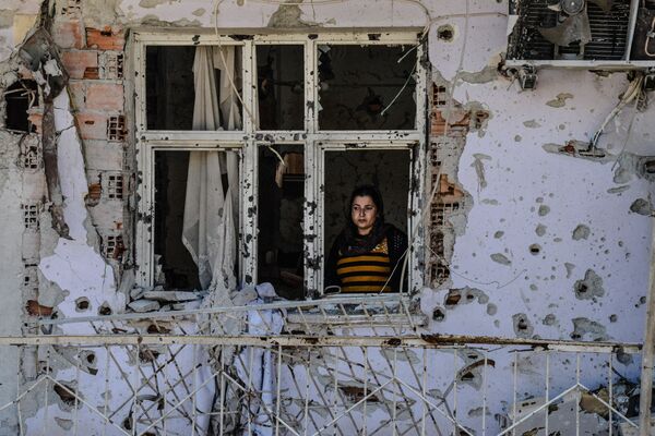 امرأة واقفة تنظر عبر نافذة بيتها المدمر في سيزر، جنوب شرق تركيا، 8 مارس/ آذار 2016. - سبوتنيك عربي