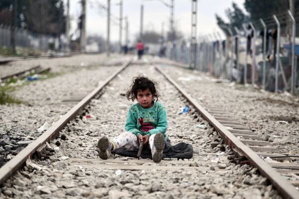 طفلة لاجئة تجلس على طريق السكة الحديدية التي تؤدي إلى الحدود اليونانية المقدونية، 7 مارس/ آذار 2016. - سبوتنيك عربي