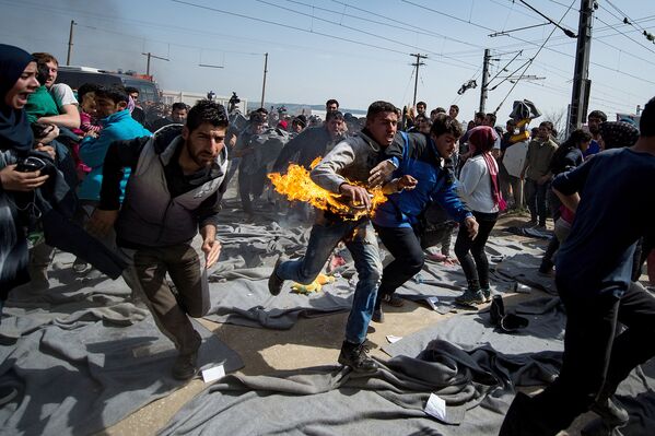 شخص تأكله النيران خلال احتجاجات على الحدود المقدونية-اليونانية، 22 مارس/ آذار 2016. - سبوتنيك عربي