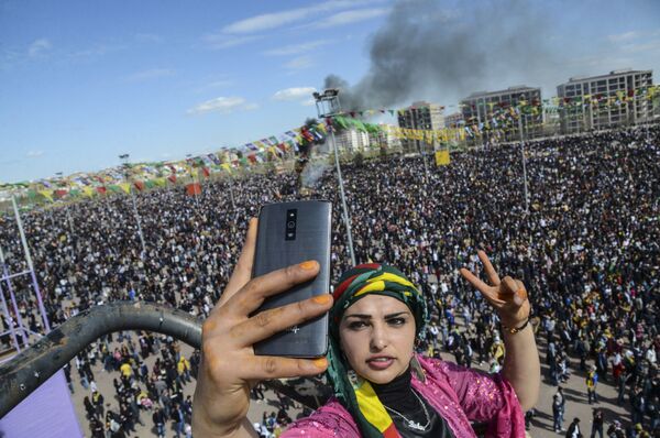 امرأة تأخذ صورة سيلفي على خلفية حشد كبير في احتفالات بعيد النيروز في ديار بكر، تركيا، 11 مارس/ آذار 2016. - سبوتنيك عربي