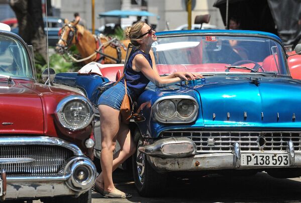 سائحة تتصور مع سيارات أمريكية قديمة في العاصمة هافانا، كوبا، 18 مالاس/ آذار 2016. - سبوتنيك عربي