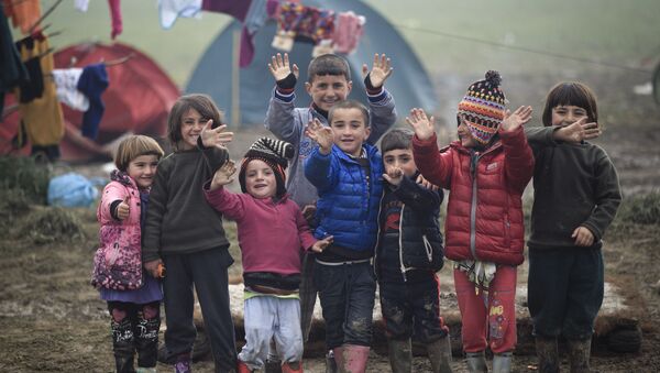 أطفال اللاجئين يلوحون بأيديهم الصغيرة للمصور، الحدود اليونانية، 18 مارس/ آذار 2016. - سبوتنيك عربي
