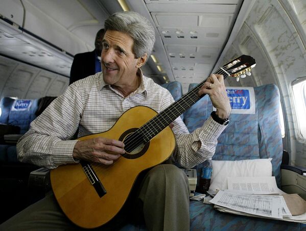 المرشح للانتخابات الرئاسية وسيناتور الأمريكي جون كيري يلعب على الغيتار على متن طائرته، وذلك خلال رحلة حملته الانتخابية، 9 مارس/ آذار 2004. - سبوتنيك عربي