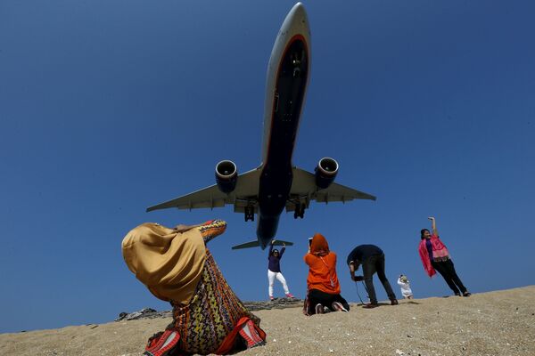السياح يلتقطون صوراً لطائرة تحلق فوق رؤوسهم، شاطئ ماي خاو القريب من المطار، في تايلاندا، 17 مارس/ آذار 2016. - سبوتنيك عربي