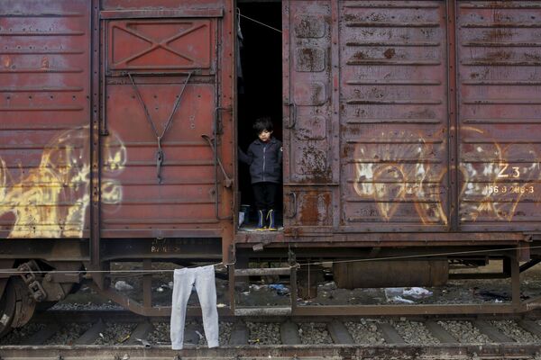 طفل لاجئ ينظر من خارج قطار في مخيم للاجئين على الحدود المقدونية-اليونانية، 28 مارس/ آذار 2016. - سبوتنيك عربي