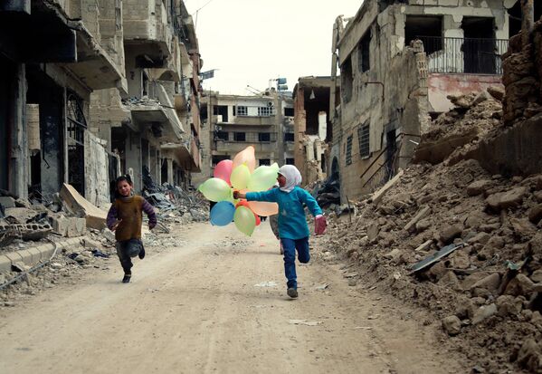 أطفال يلعبون بين دمار الحرب بالضواحي الشرقية للعاصمة السورية دمشق، 9 أبريل/ نيسان 2016 - سبوتنيك عربي