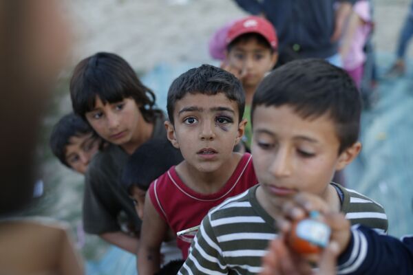 الأطفال المهاجرون يقفون في طابور للحصول على الألعاب في مخيم للاجئين باليونان، 17 أبريل/ نيسان 2016. - سبوتنيك عربي