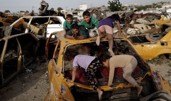 أطفال غزيوو يلعبون بين اليارات القديمة والمدمرة في خان يونس، قطاع غزة 9 مايوم/ آيار 2016. - سبوتنيك عربي