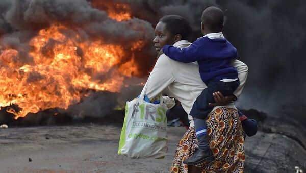 امرأة تحمل طفلها وتمر بالعجلات الحارفة في شوارع نيروبي بكينيا، 23 مايو/ آيار 2016. - سبوتنيك عربي