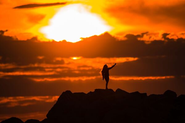 فتاة تلتقط صورة سيلفي لها على خلفية غروب الشمس في أدلير - سبوتنيك عربي