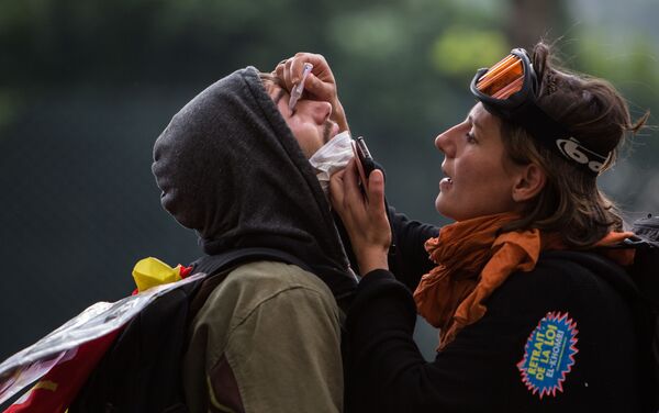 أحد المتظاهرين يساعد الآخر في معالجة العينين أصيبت بغاز المسيل للدموع خلال الاشتباكات مع الشرطة الفرنسية في باريس - سبوتنيك عربي