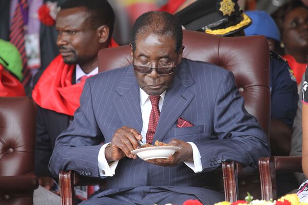 رئيس زيمبابوي روبيرت موغابي يأكل قطعة الكيك خلال الاحتفال بعيد ميلاده الـ 92، عام 2016 - سبوتنيك عربي