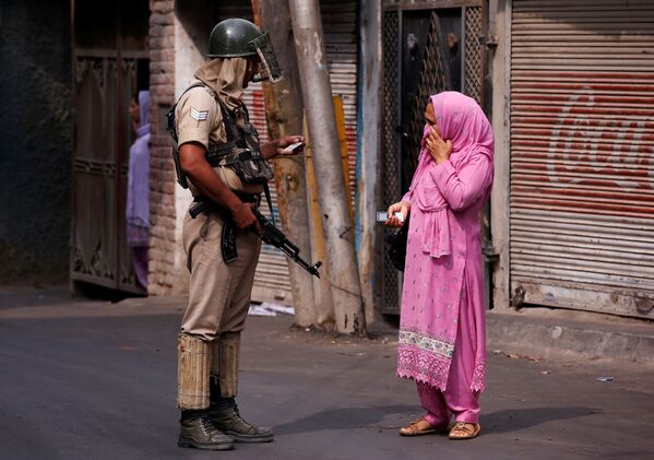 شرطي هندي يفتش هوية امرأة خلال حظر التجوال في سريناغار، الهند 14 يوليو/ تموز 2016 - سبوتنيك عربي