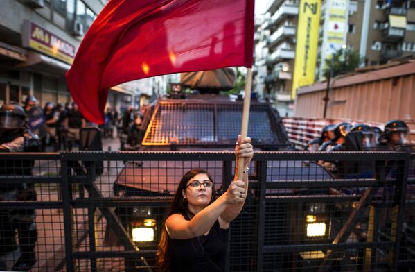 امرأة تحمل راية حمراء أمام شرطة الشغب في مظاهرة مناهضة للحكومة المقدونية، مدينة سكوبيه 11 يوليو/ تموز 2016 - سبوتنيك عربي