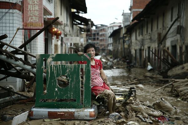 امرأة تجلس وسط شارع في الصين بعد طوفان ضرب البلاد، 10 يوليو/ تموز 2016. - سبوتنيك عربي