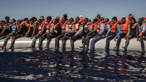 لاجئون من إرتيريا ومالي وبنغلادش (ودول أخرى) ينتظرون قارب نجاة في البحر الأبيض المتوسط على بعد 27 كم من شواطئ ليبيا، يوليو/ تموز 2016 - سبوتنيك عربي