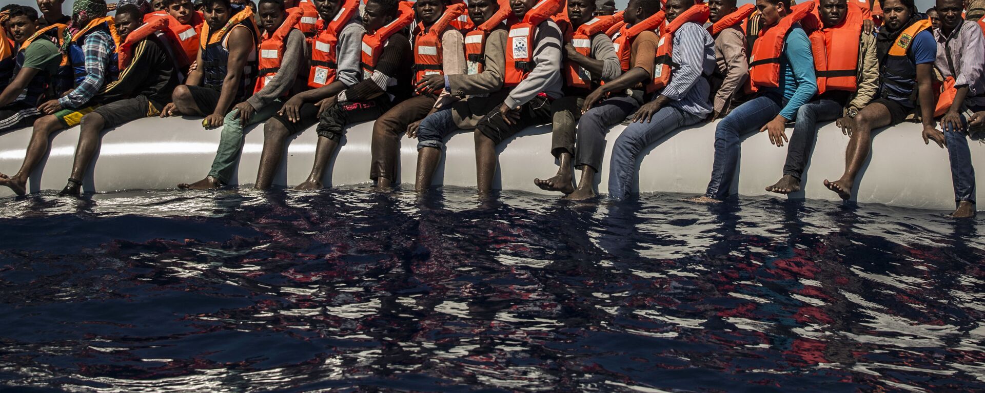 لاجئون من إرتيريا ومالي وبنغلادش (ودول أخرى) ينتظرون قارب نجاة في البحر الأبيض المتوسط على بعد 27 كم من شواطئ ليبيا، يوليو/ تموز 2016 - سبوتنيك عربي, 1920, 22.05.2017