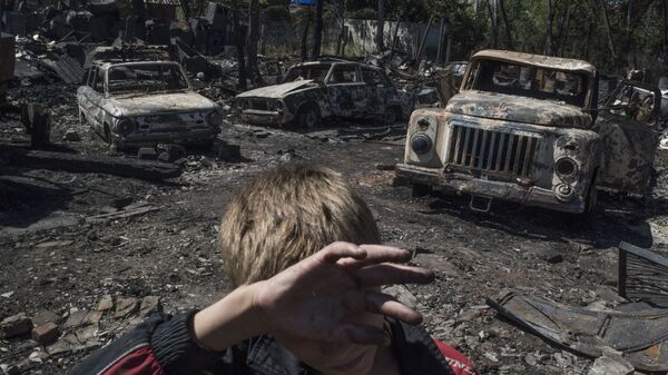 مراهق على خلفية دمار خلّفه قصف بقرية لوزوفوي في جمهورية دونيتسك، أوكرانيا - سبوتنيك عربي