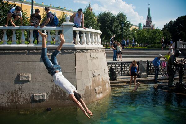 الكبار والصغار يسبحون في نافورة المياه غيروي سكازك (أبطال القصص) على ساحة مانيجنايا في موسكو - سبوتنيك عربي