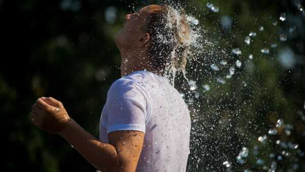 رجل يهرب من حر الجو إلى نافورة المياه زافيسا على ساحة مانيجنايا في موسكو - سبوتنيك عربي
